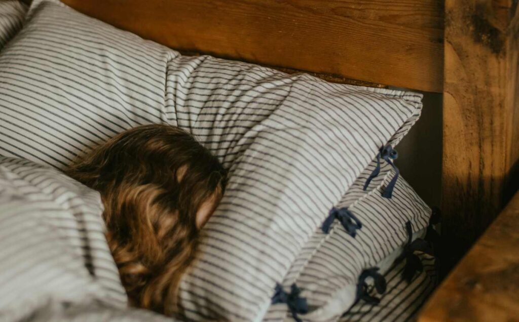 The head of a child sleeping can just be seen, between white and striped bedding.