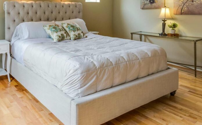 A plush bed with white bedding on wooden floors. Choosing the Right Mattress.