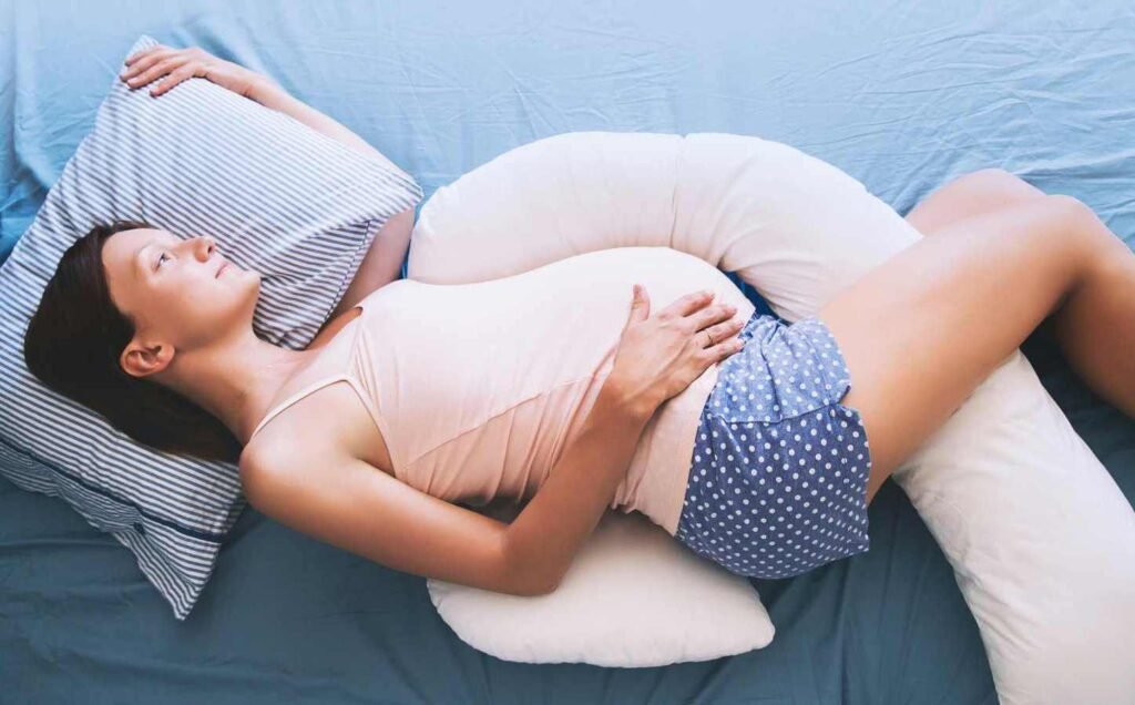 A pregnant woman laying on her side using pillows to maintain a healthy sleeping position.