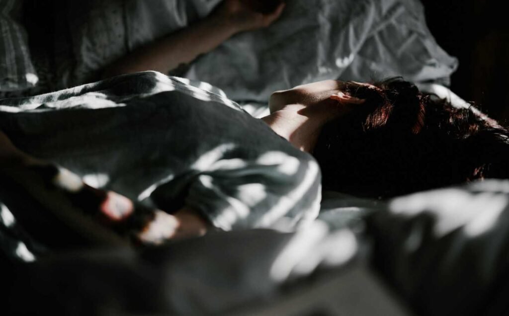 A person sleeping soundly on a bed that is partly in the shadows. Discover how progressive muscle relaxation for sleep can enhance your sleep.