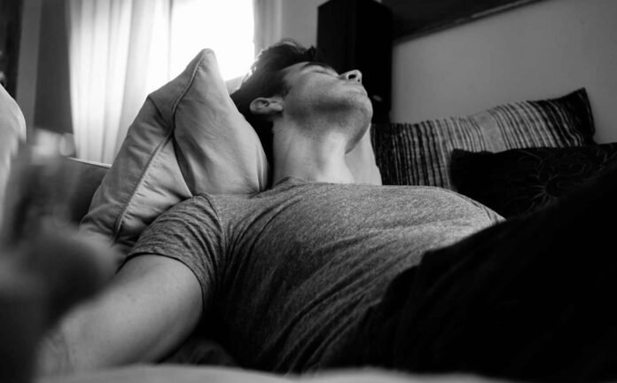 A black and white photo of a man asleep on his back.