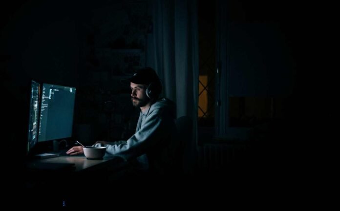 Male wearing headphones at his computer late at night. What is the ROI of sleeplessness.