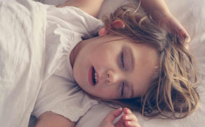 A young child sleeping with her hands up beside her head. Its all about Childhood Sleep Quality.