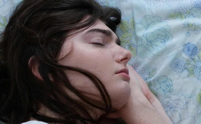 Head shot of a young woman sleeping. Her head is resting on her hands. Depicting the importance of REM sleep.