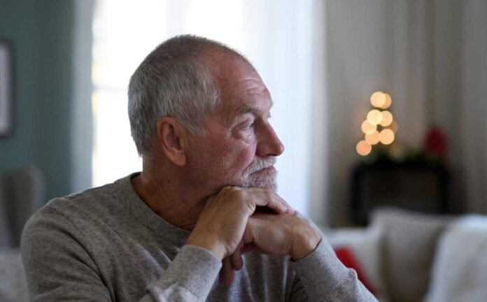 An elderly grey haired male looking to the left looking into the distance.