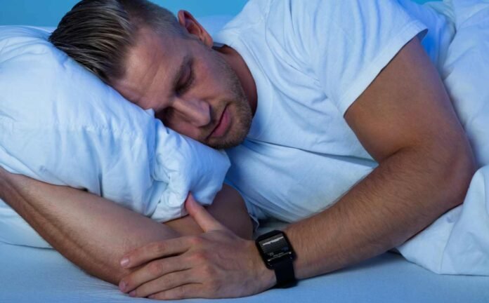 Man sleeping on his side, one arm under the pillow supporting his head.