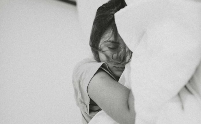 A black and white photo of a young woman sleeping, with one arm exposed.