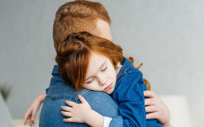 A father holding his sleeping daughter, before taking The Epworth Sleepiness Scale for Children.