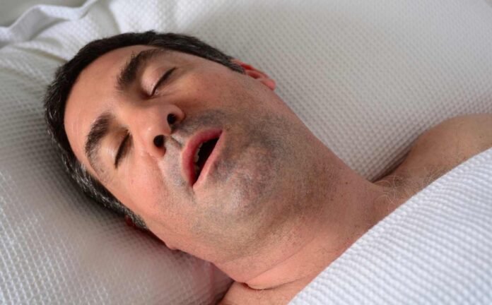 A man in bed snoring.