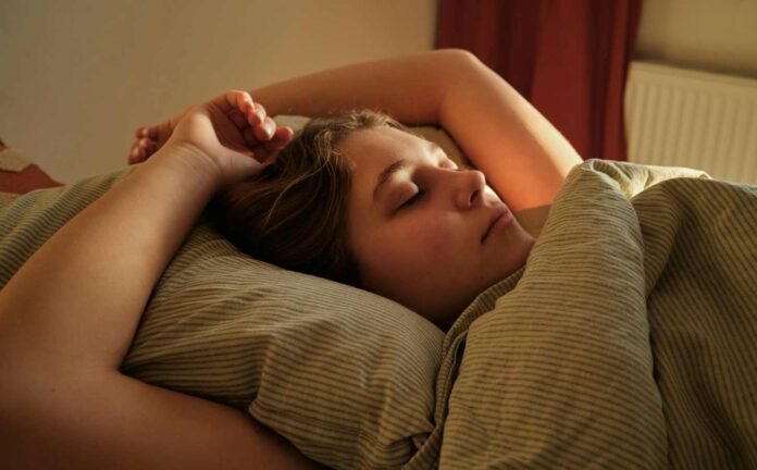 A teenage female asleep in bed. She possibly shows signs of Kleine Levin Syndrome Symptoms.