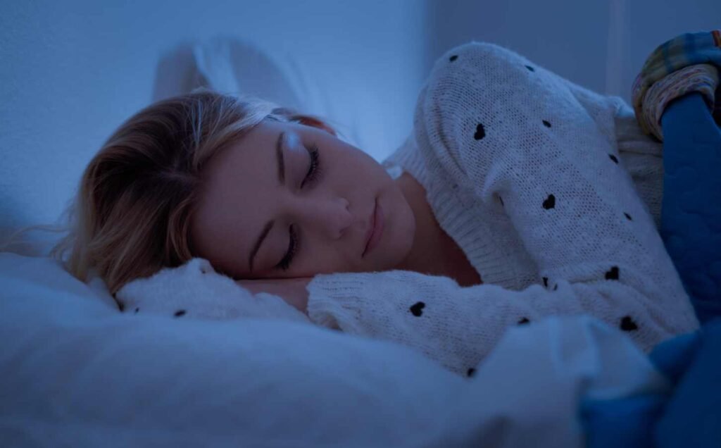 A young woman asleep om her side facing the camera.