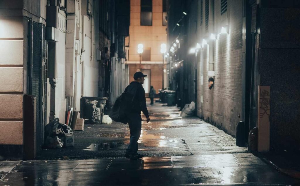 A man walking past an ally way late at night. He is likely to experience Shift Work Sleep Disorder.