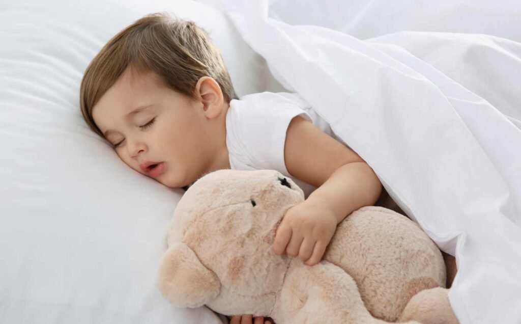 A baby boy sleeping with bis teddy bear, primary snoring.