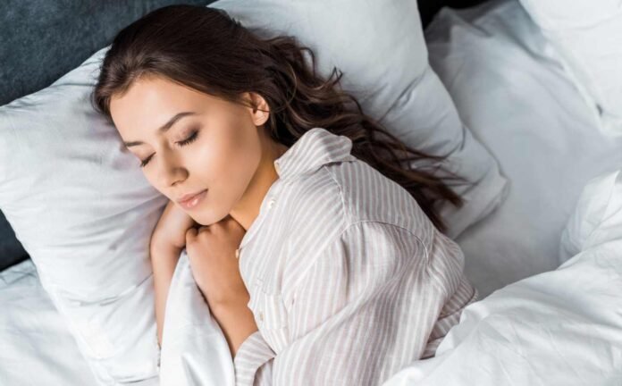 A woman cuddled up in bed asleep.