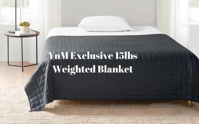 A bed with a dark grey YnM Exclusive weighted blanket.