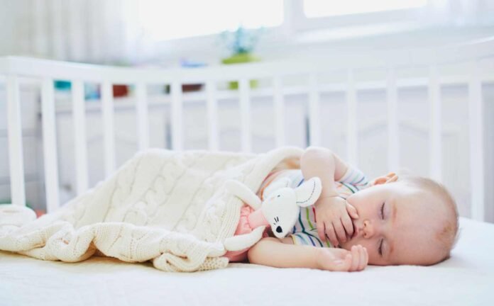 A baby sleeping in a white crib.