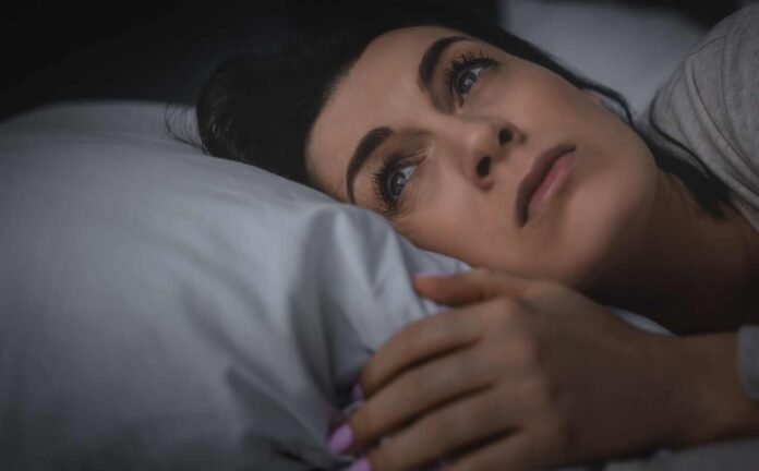 A woman awake in bed suffering from Insomnia