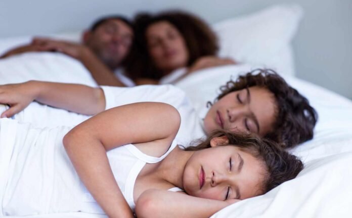 A family of four asleep in bed.